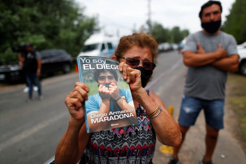 Foto del miércoles de una mujer sosteniendo el libro biográfico de Diego Maradona "Yo soy el Diego" duera de la casa en la que vivia en Tigre, en las afueras de Buenos Aires