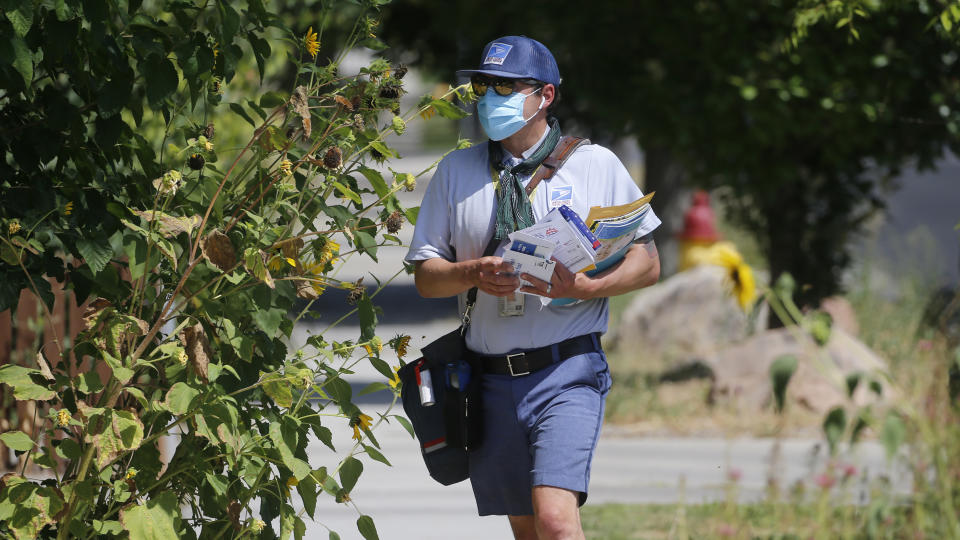 A United States Postal Service carrier delivers mail to a home Monday, Aug. 17, 2020, in Salt Lake City. (AP Photo/Rick Bowmer)