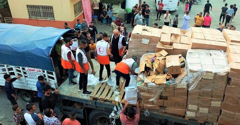 Members of the Palestine Red Crescent Society distribute aid to people in Khan Younis