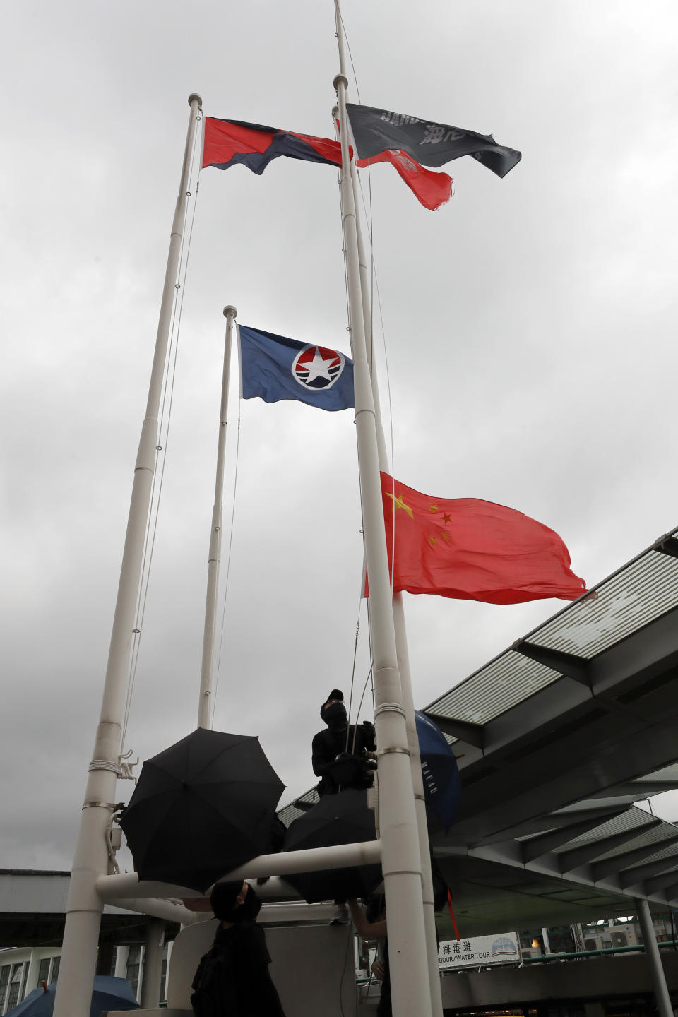 A protester lowers a Chinese flag from a flagpole during a demonstration in Hong Kong, Saturday, Aug. 3, 2019. Hong Kong protesters ignored police warnings and streamed past the designated endpoint for a rally Saturday in the latest of a series of demonstrations targeting the government of the semi-autonomous Chinese territory. (AP Photo/Vincent Thian)