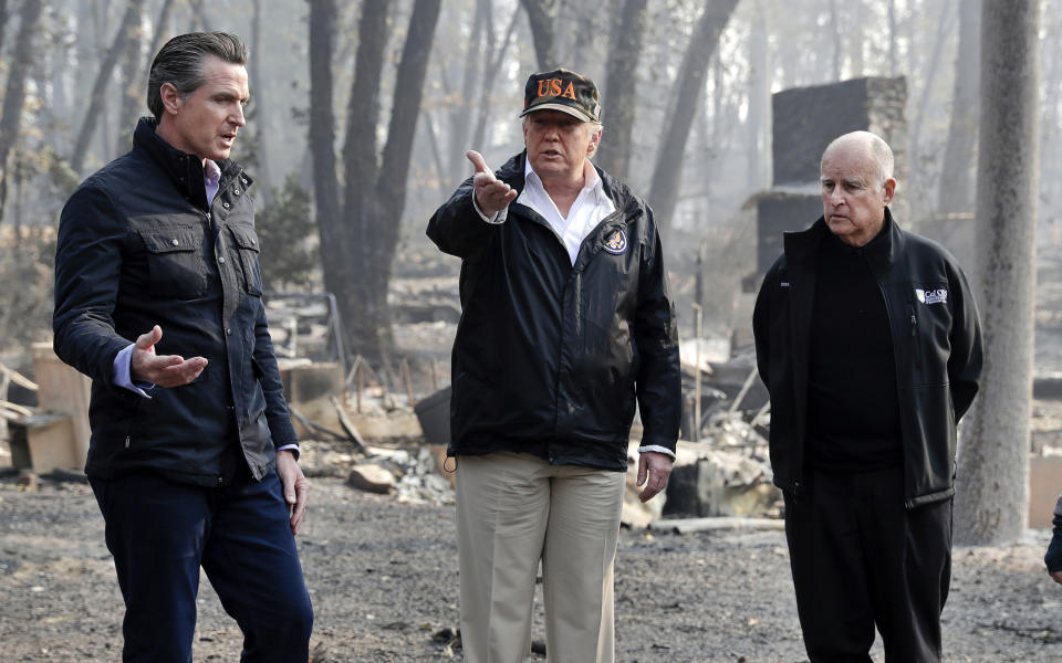 FILE - In this Nov. 17, 2018, file photo, President Donald Trump talks with then Gov.-elect Gavin Newsom, left, and as California Gov. Jerry Brown listens during a visit to a neighborhood impacted by the wildfires in Paradise, Calif. California Gov. Gavin Newsom says the Trump administration is engaging in "political retribution" by trying to take back $3.5 billion granted for the state's high-speed rail project. The Democratic governor says President Donald Trump is reacting to California suing over Trump's emergency declaration to pay for a wall along the U.S.-Mexico border. (AP Photo/Evan Vucci, File)