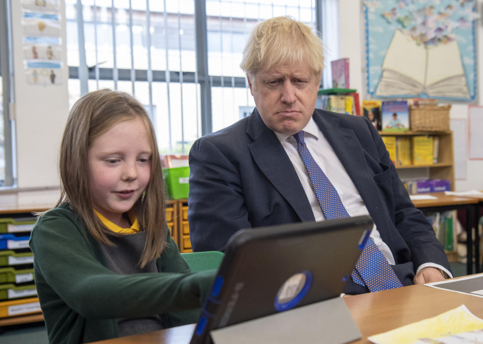 Britain's Prime Minister Boris Johnson, right, reacts with pupils during a visit to Middleton Primary School in Milton Keynes, England, Friday Oct. 25, 2019. European Union ambassadors agreed Friday that the bloc should grant Britain’s request for another extension to the Brexit deadline but have not yet figured out how long that delay should be. (Paul Grover/Pool via AP)