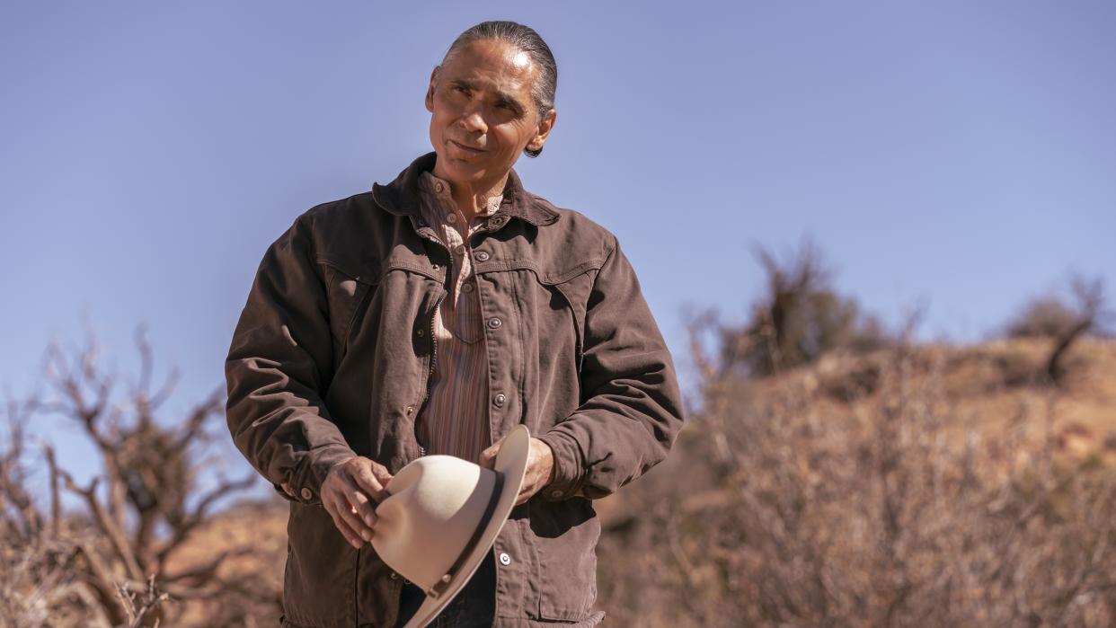  Zahn McClarnon as Joe Leaphorn in Dark Winds holding a hat in Dark Winds season 1. 