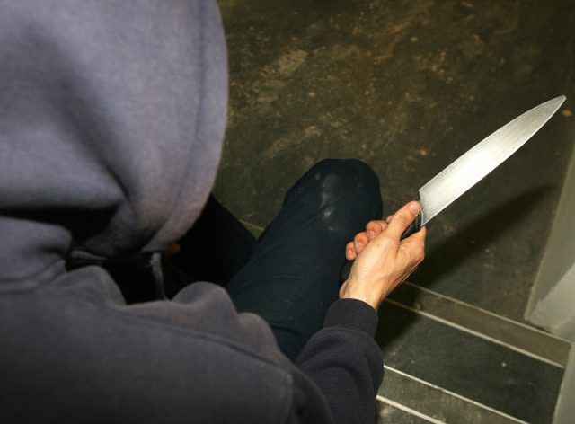 A general view of a teenager in a hoodie holding a knife