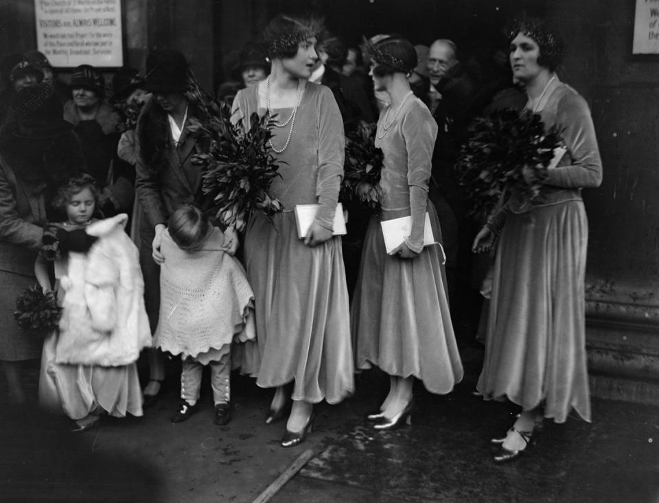 <p>Luxe fabrics of the era, such as velvet, were common for bridesmaids dresses. Here, the bridal party is seen in velvet long sleeve dresses, double stranded pearls, and a head wrap. </p>