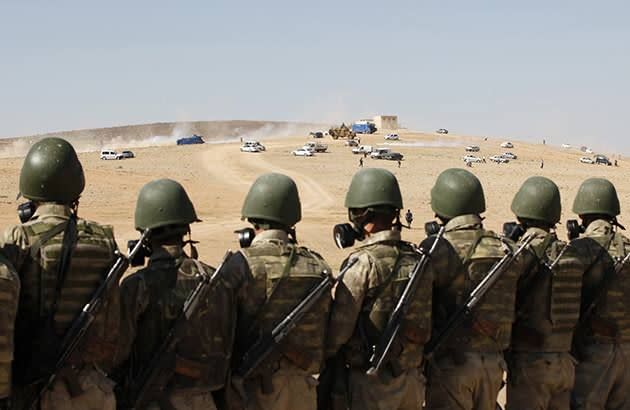 Turkish soldiers stand guard as protesters run away from tear gas during a pro-Kurdish demonstration in solidarity with the people of Kobani. Photo: Getty