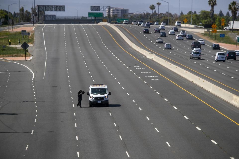 An investigator takes photographs on the northbound 55 Freeway, near where Aiden Leos was fatally shot on May 21.