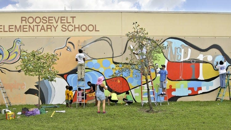 An artist and volunteers paint a mural at Roosevelt Elementary School in 2014.