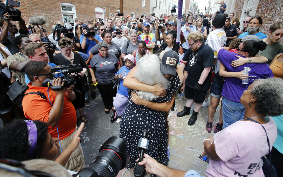 Susan Bro, center back to camera, mother of Heather Heyer who was killed during last year's Unite the Right rally, embraces a supporter after laying flowers at the spot her daughter was killed in Charlottesville, Va., Sunday, Aug. 12, 2018. Last year, white supremacists and counterprotesters clashed in the city streets before a car driven into a crowd struck and killed Heyer. (AP Photo/Steve Helber)