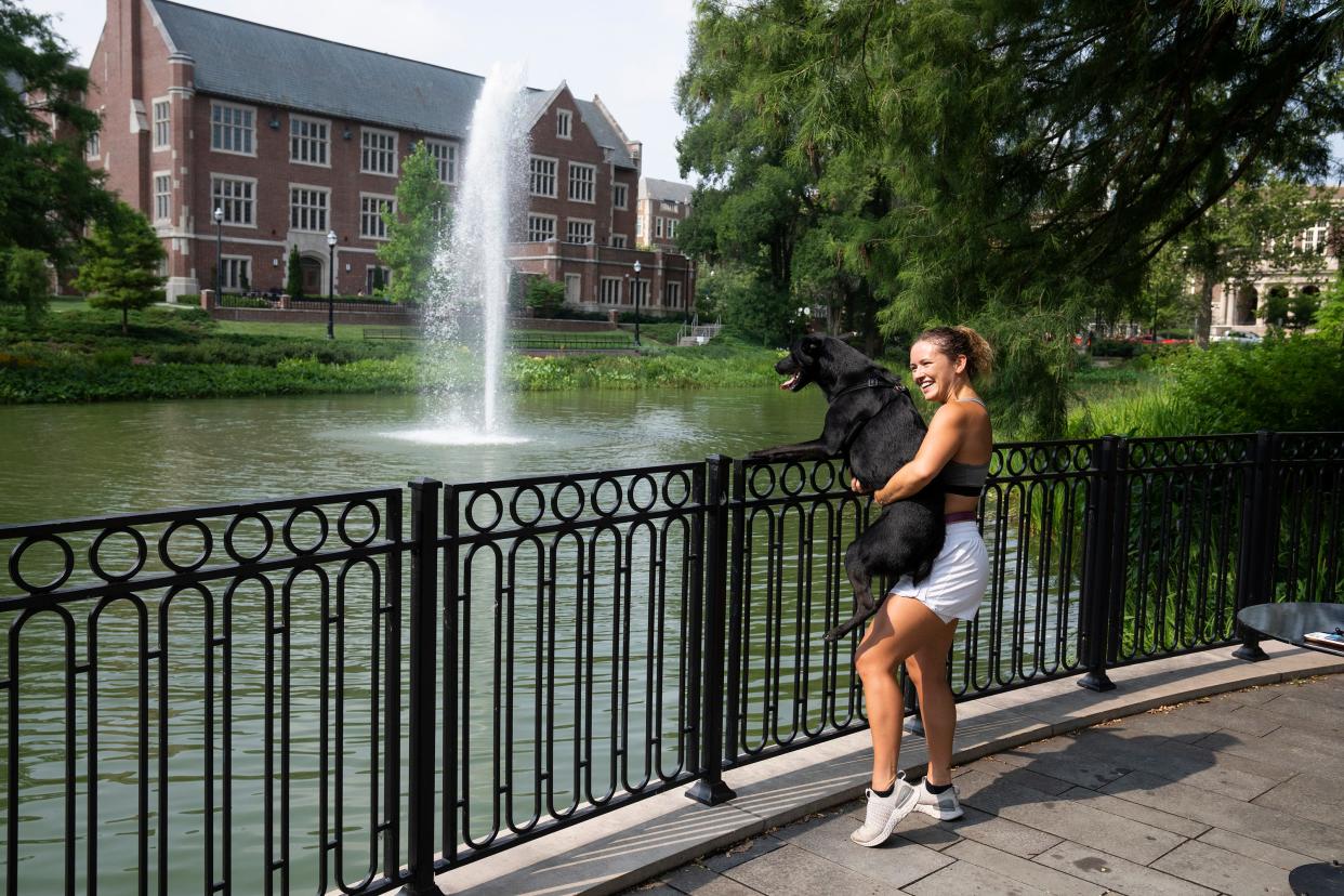 Jul 18, 2023; Columbus, Ohio, United States; Adrianna Grothouse holds her dog Rosey above the railing to see the ducks during their run on The Ohio State University campus near Mirror Lake. 