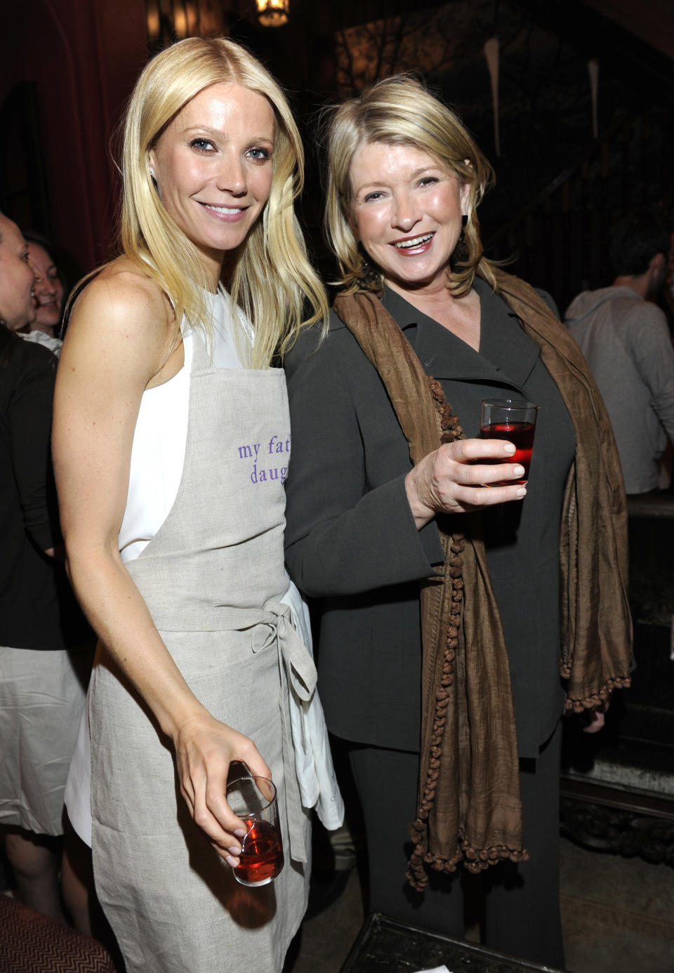 Gwenyth Paltrow, wearing an apron, poses next to Martha Stewart at an event