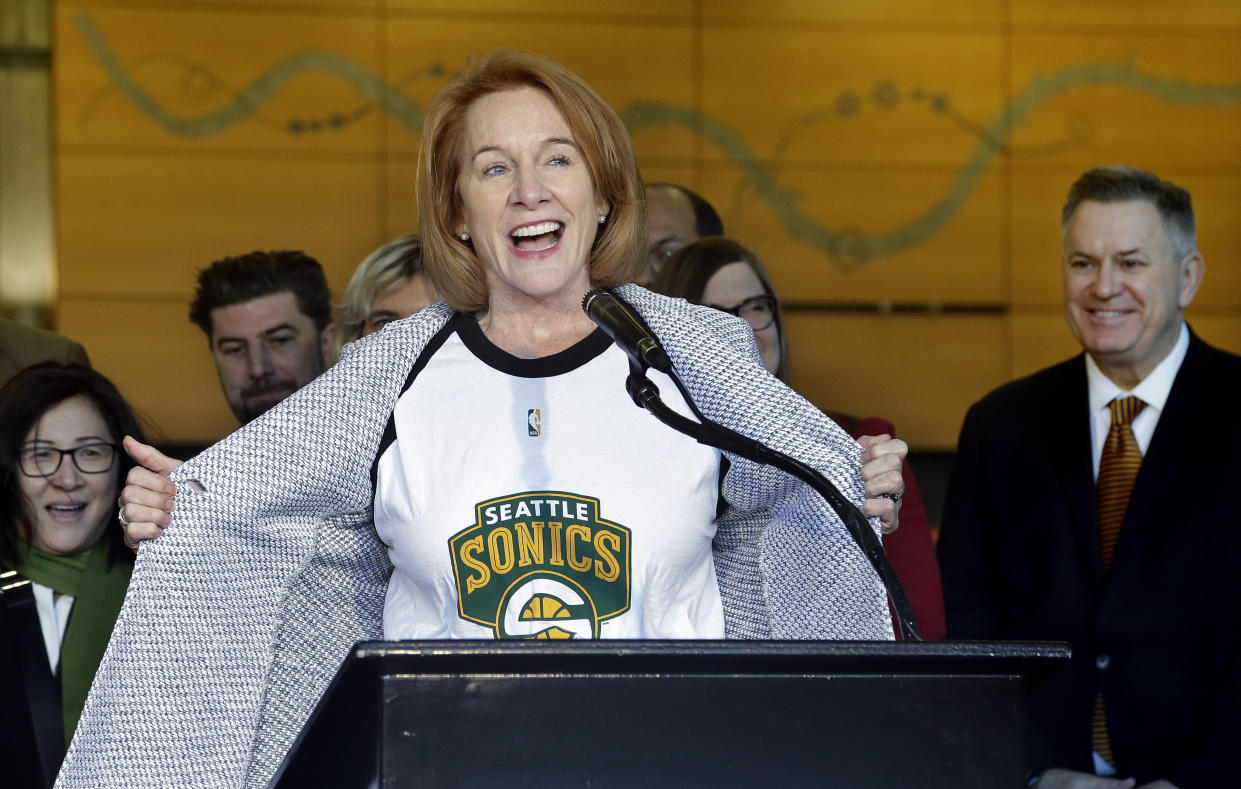 Seattle mayor Jenny Durkan pulls back her jacket to reveal a Seattle SuperSonics T-shirt as Tim Leiweke (right), the CEO of Los Angeles-based Oak View Group, looks on. (AP)