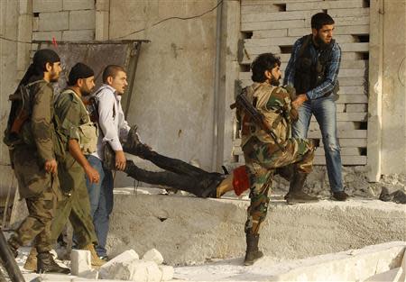 Free Syrian Army fighters carry a body of a fellow fighter who was killed by what the FSA said was during clashes with forces loyal to Syria's President Bashar al-Assad near Base 80 near Aleppo International airport, November 8, 2013. REUTERS/Molhem Barakat