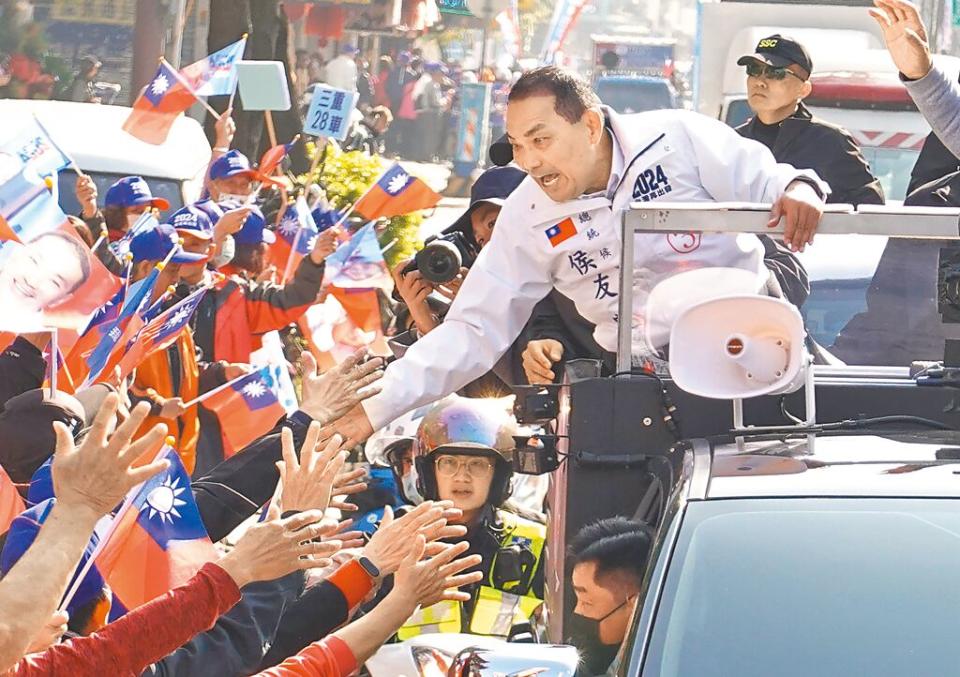 國民黨總統候選人侯友宜（中）5日以車隊方式在新北市三重區掃街拜票，並彎下腰與路旁支持者擊掌致意。（姚志平攝）