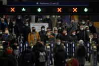 Commuters walk through ticket barriers in Waterloo train station, London, after disembarking from a train, Monday, Nov. 29, 2021. The new potentially more contagious omicron variant of the coronavirus popped up in more European countries on Saturday, just days after being identified in South Africa, leaving governments around the world scrambling to stop the spread. In Britain, Prime Minister Boris Johnson said mask-wearing in shops and on public transport will be required, starting Tuesday. (AP Photo/Matt Dunham)