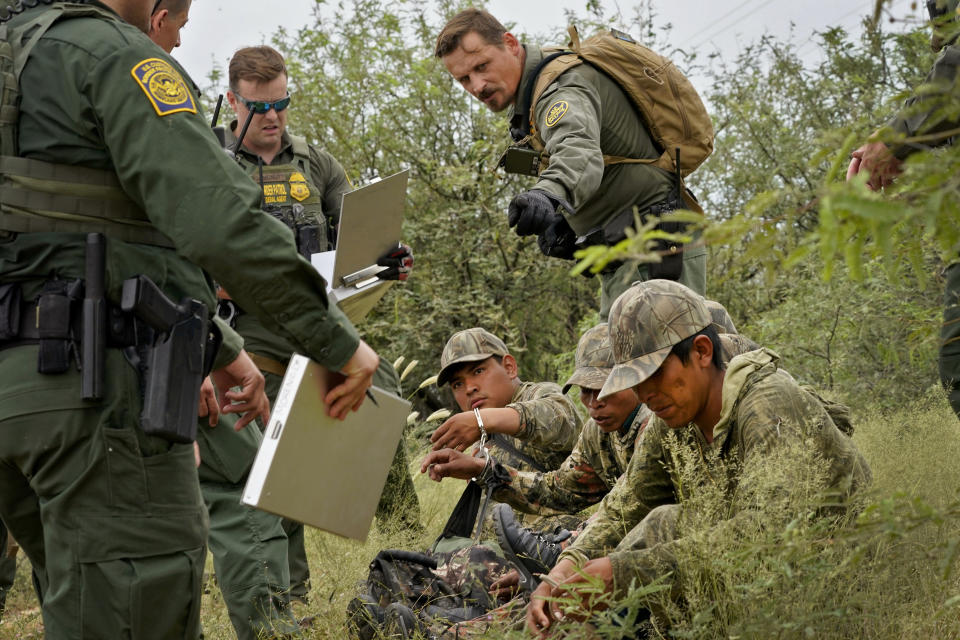 Apprehended migrants are processed by U.S. Border Patrol agents in the desert brush at the base of the Baboquivari Mountains, Thursday, Sept. 8, 2022, near Sasabe, Ariz. The desert region located in the Tucson sector just north of Mexico is one of the deadliest stretches along the international border with rugged desert mountains, uneven topography, washes and triple-digit temperatures in the summer months. Border Patrol agents performed 3,000 rescues in the sector in the past 12 months. (AP Photo/Matt York)
