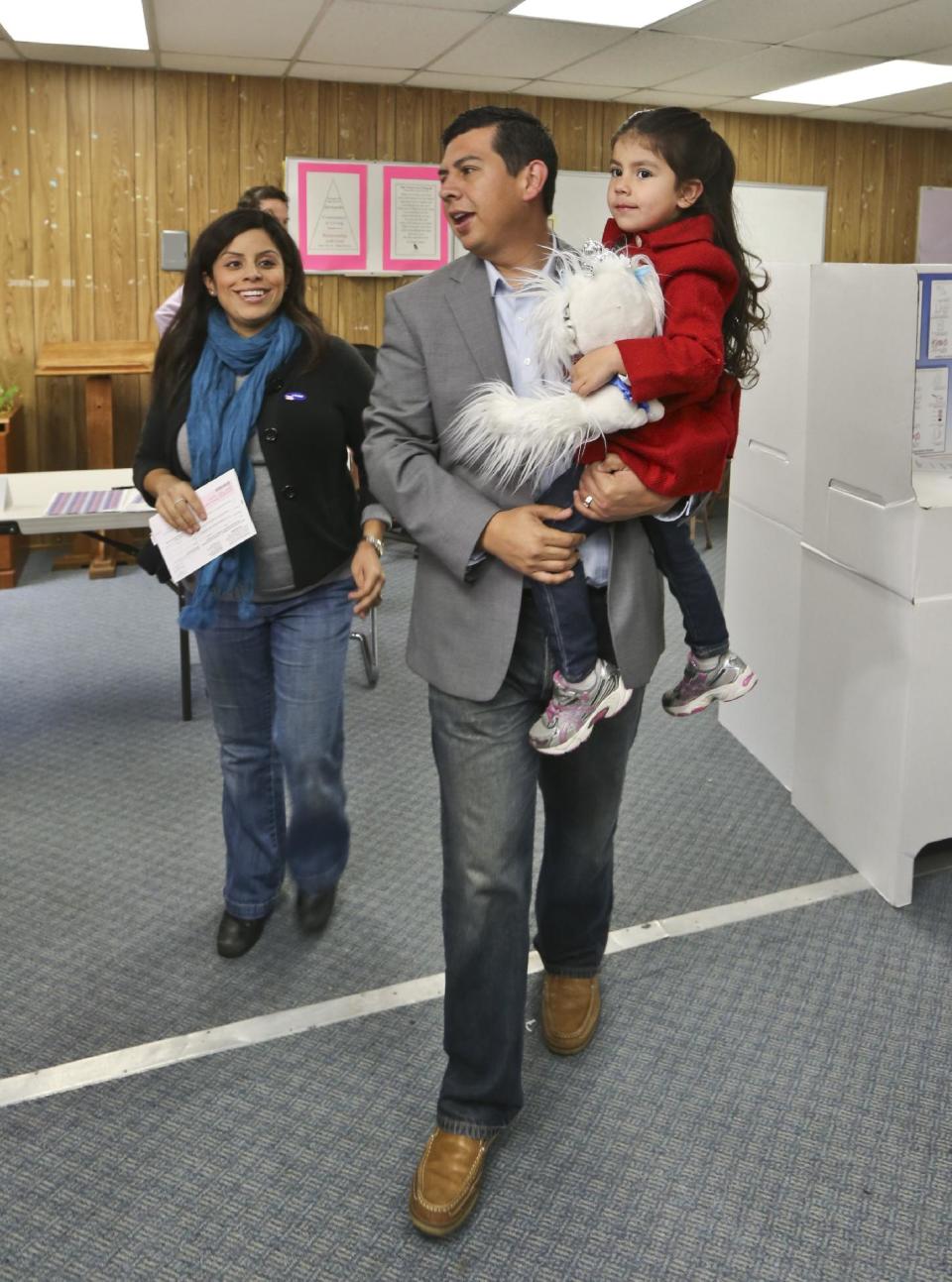 San Diego mayoral candidate David Alvarez, carries his daughter, Izel, as he and his wife, Xochitl, leave the polling location where they voted in the Logan Heights neighborhood where Alvarez grew up and still lives Tuesday, Feb. 11, 2014 in San Diego. (AP Photo/Lenny Ignelzi)