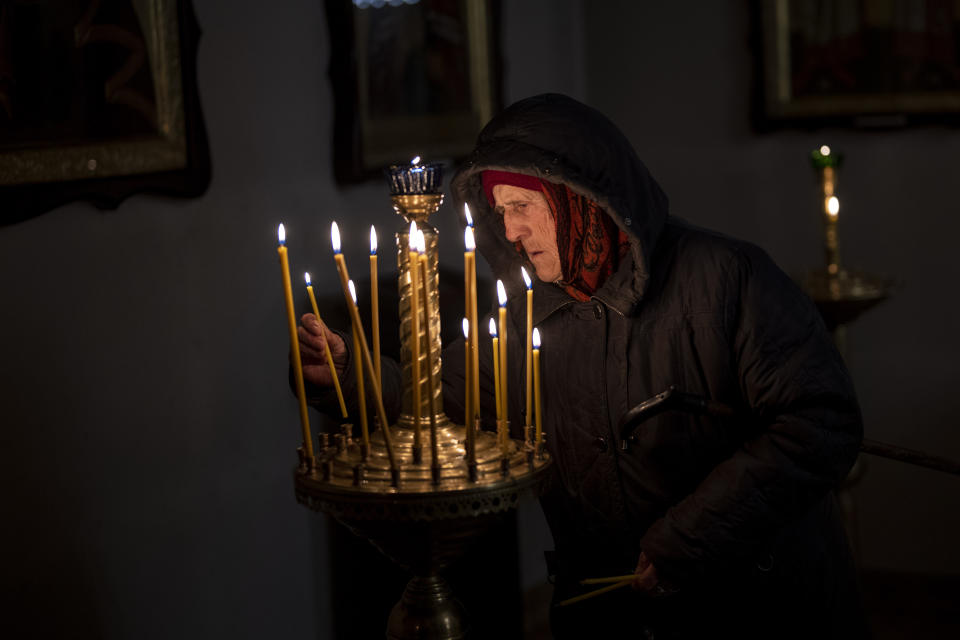 A woman lights candles during an Easter religious service celebrated at a church in Bucha, in the outskirts of Kyiv, on Sunday, April 24, 2022. (AP Photo/Emilio Morenatti)