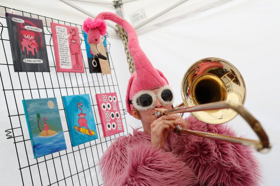 The Athens Pink Flamingo plays a song after selling a painting at their Indie South booth at Bishop park in Athens, Ga., on Saturday, Dec. 9, 2023.