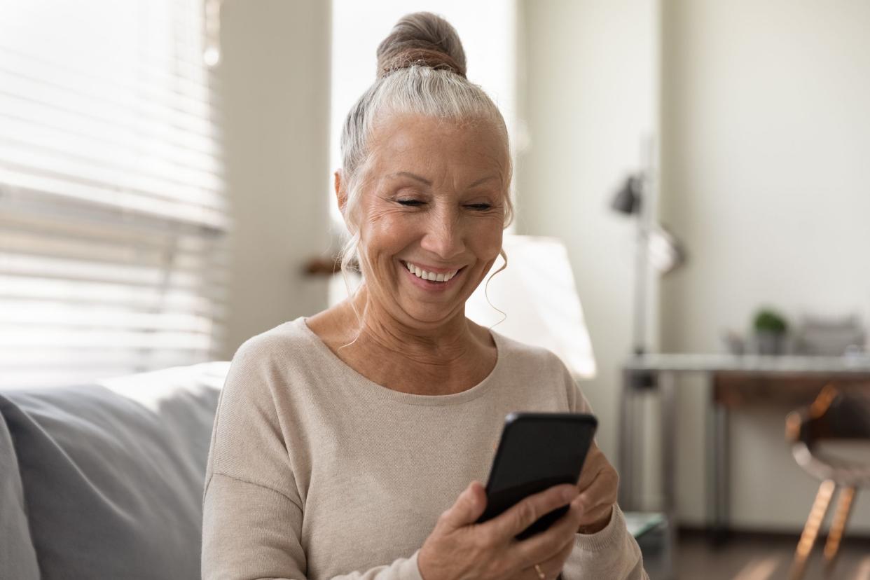 Elderly generation and modern tech. Smiling senior female use mobile phone app look at screen enjoy playing game. Happy aged woman retiree holding cell gadget chatting texting online watching video