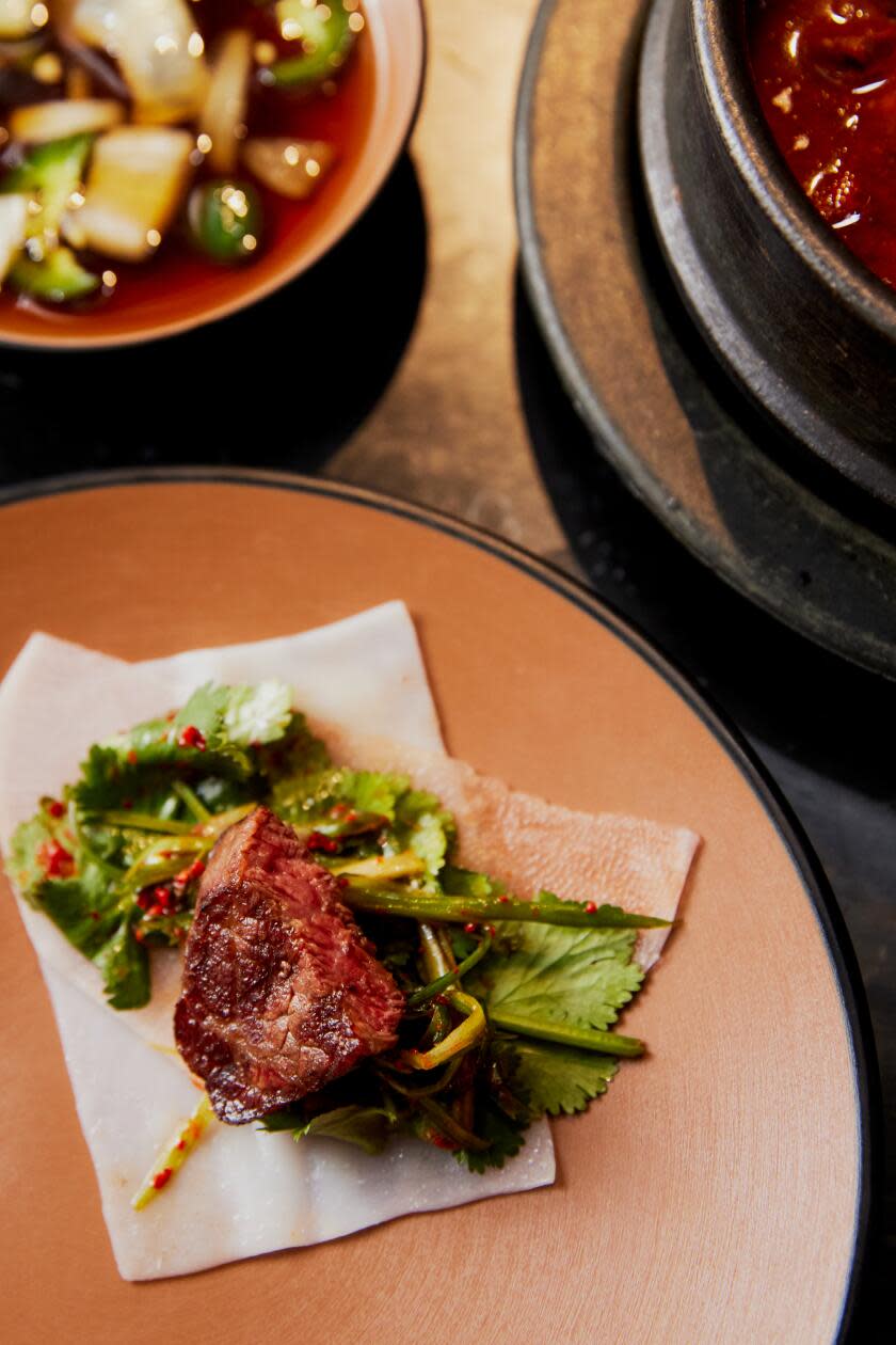 The ideal bite of grilled meat, cilantro, pickled radish on a rice wrapper at Korean BBQ at the Source OC.