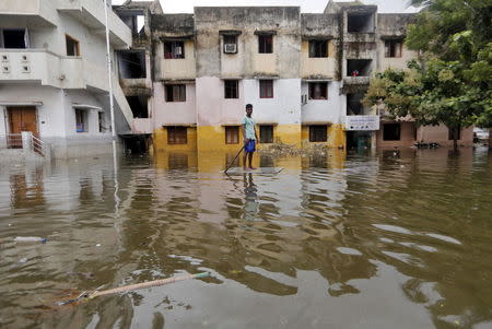 A man uses a board to float through a flooded street to reach to a market place in Chennai, India, December 5, 2015. REUTERS/Anindito Mukherjee