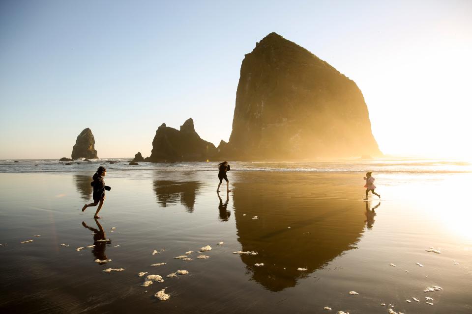 Kids chase one another as the sun silhouettes Haystack Rock on Sunday, Aug. 23, 2020 in Cannon Beach, Oregon. 