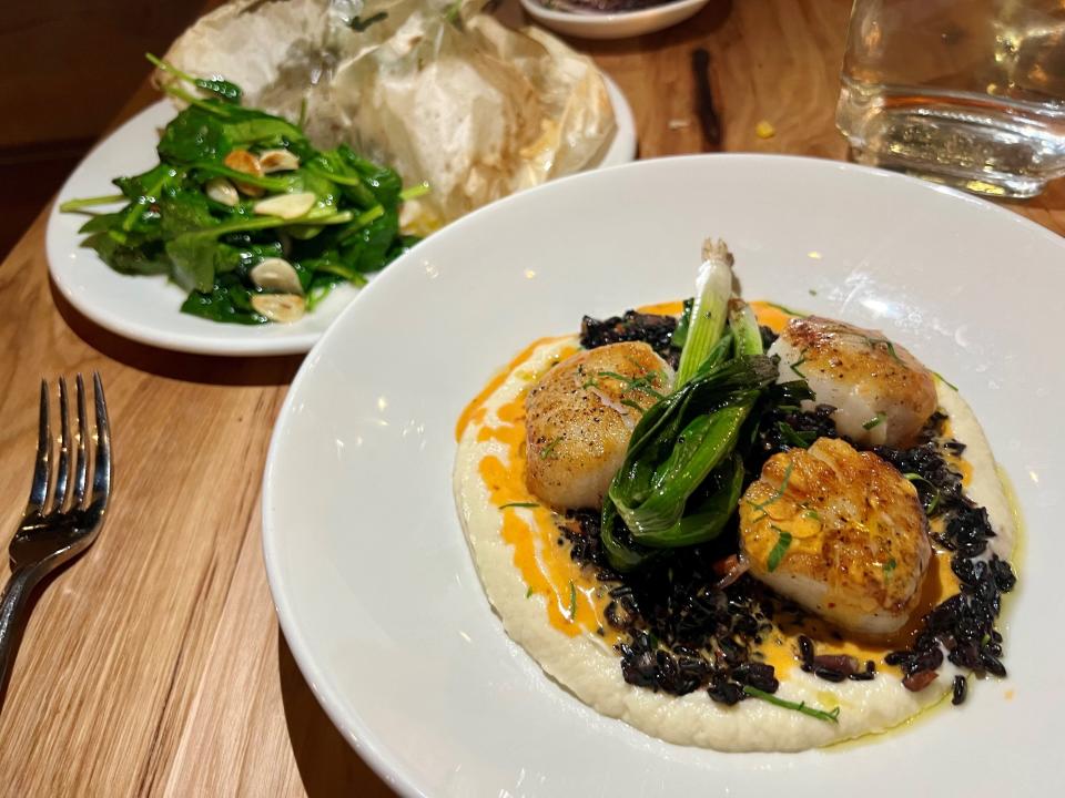 Sea scallops with forbidden black rice, celery root crema, charred scallion, n'duja, butter sauce and marcona at Bestia Mare seafood restaurant in Franklin, Tenn., on Feb. 20,2024