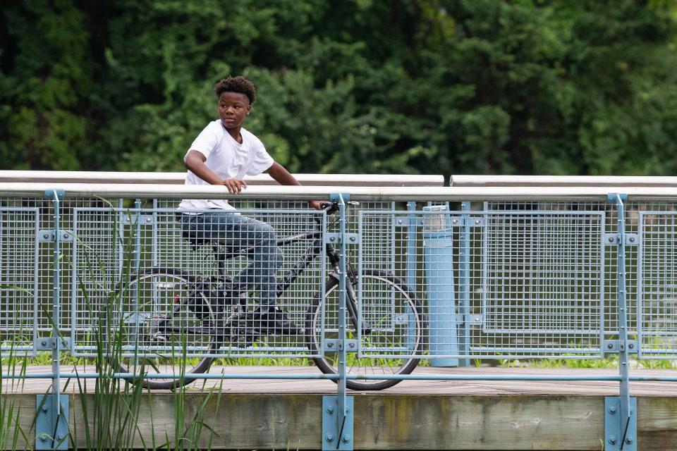 A visitor rides his bike by the Riverfront Market near Wilmington's Riverwalk, Thursday, Aug. 17, 2023. The Riverwalk is 1.75 miles long.