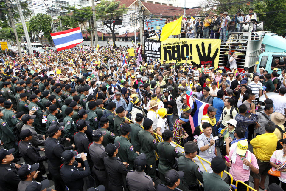 Thai police officers, left, and members of the People's Alliance for Democracy (PAD) demonstrators, right, confront at a street leading to parliament house Friday, June 1, 2012. Thai politics has shifted its focus to the streets again after thousands of protesters have deterred lawmakers from deliberating a bill they claimed could whitewash the wrongdoing of politicians and bring back ousted premier Thaksin Shinawatra. (AP Photo/Wason Wanichakorn)