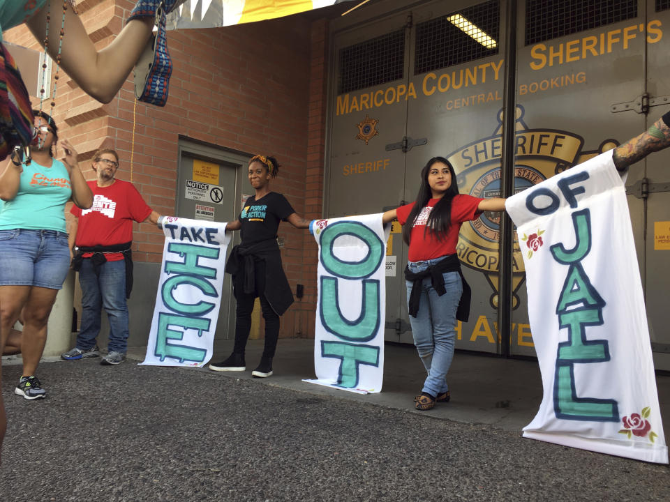 A group of protesters chain themselves to each other outside the Maricopa County Jail in downtown Phoenix during a protest against the sheriff's relationship with Immigration and Customs Enforcement Wednesday, Aug. 22, 2018. Over 100 activists gathered outside the jail to protest Sheriff Paul Penzone's continued cooperation with U.S. Immigration and Customs Enforcement authorities. Four people were arrested. (AP Photo/Astrid Galvan)