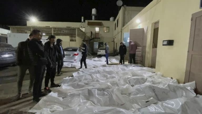 En esta imagen tomada de un video, gente mira algunos de los cuerpos llegados al hospital de Al Aqsa en Deir el Balah, Franja de Gaza, la noche del 24 de diciembre de 2023 después de tres ataques aéreos en el centro de Gaza. (AP Foto)