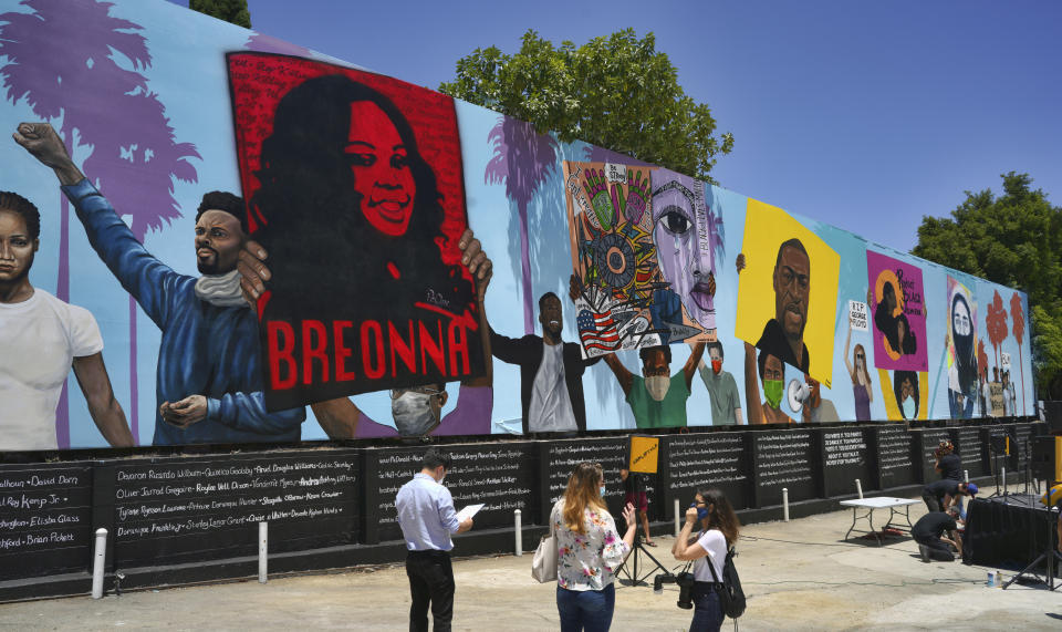 Visitors arrive for the unveiling of a 148-foot tribute mural to Black Lives Matter in Los Angeles on Tuesday, July 7, 2020. The artwork was created by five African American artists, Alexandra Allie Belisle, Amanda Ferrell Hale, Noah Humes, PeQue Brown, and Shplinton. Said to be the largest in the nation the mural was commissioned by Los Angeles Fourth District Councilmember David Ryu and the Laugh Factory. (AP Photo/Richard Vogel)