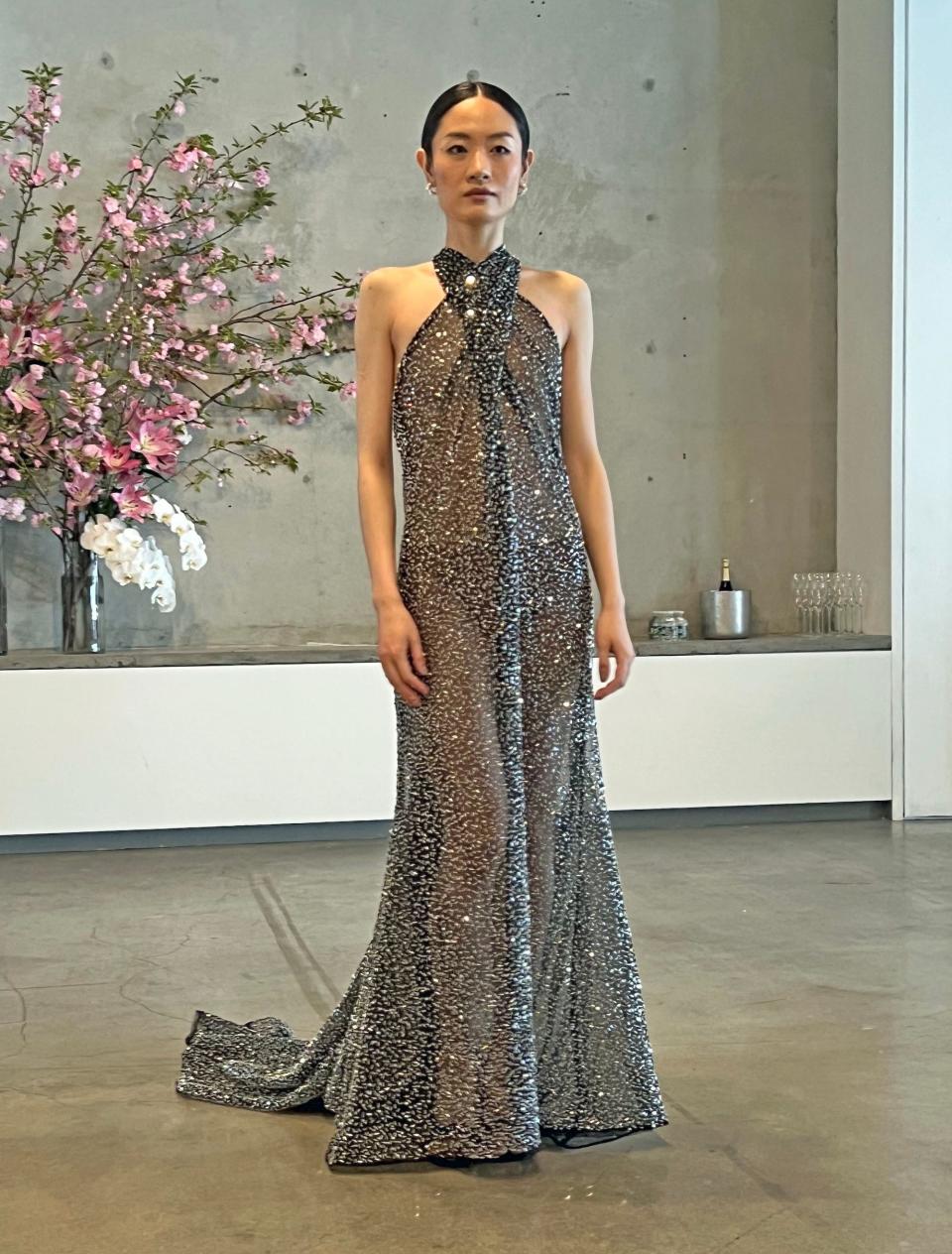 A woman poses in a sparkly, sheer dress.