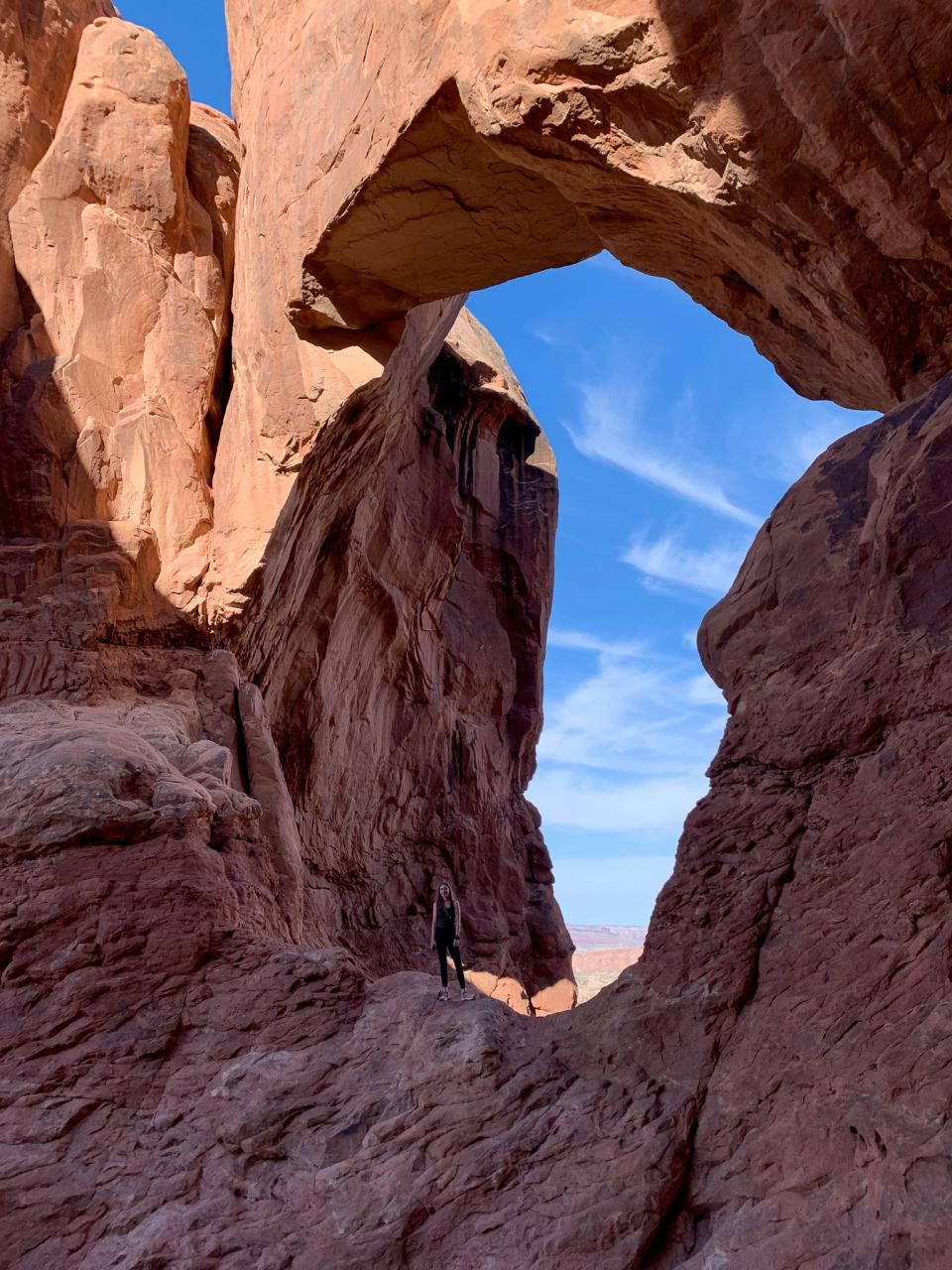 The author stands underneath an arch in Arches National Park.