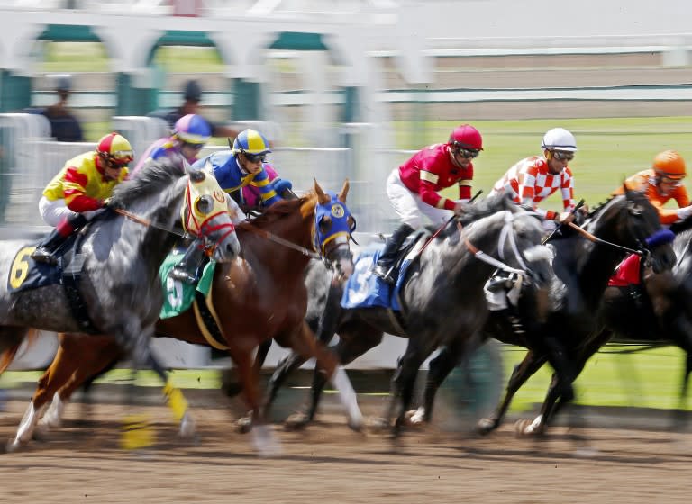 LOS ALAMITOS, CALIF. - JUNE 29, 2019. Horses and jockeys charge out of the starting gate during the sixth race.