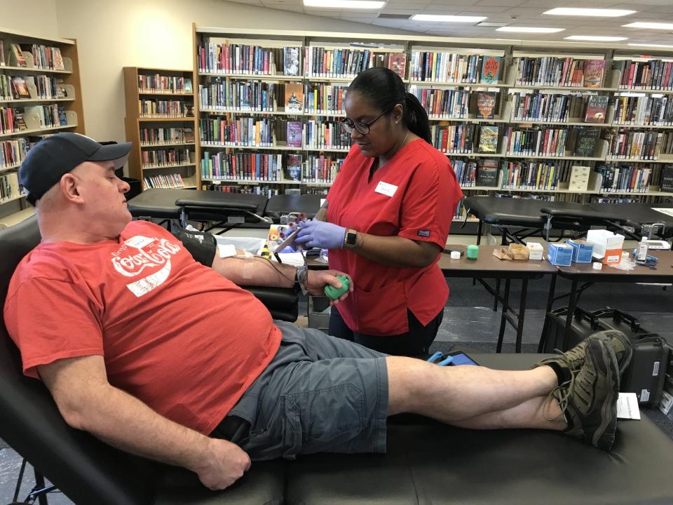 Randal Rosenberger donates a pint of blood while surrounded by shelves of books and DVDs at the Frenchtown-Dixie Branch Library recently. Dominique Sanders, a phlebotomist for the American Red Cross, assists him with the donation. A retired sheriff's deputy, Rosenberger, 53, has donated his A-positive blood type for about 30 years. Several blood drives will be held this month in Monroe County.