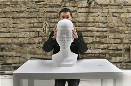 Chinese artist Li Hongbo shows his paper sculpture work, made of 6,000 pieces of paper, while raising it at his studio on the outskirts of Beijing, January 20, 2014. REUTERS/Jason Lee