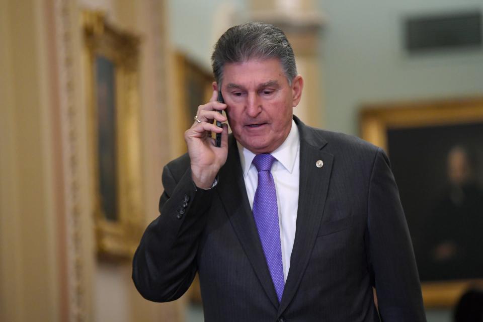 Sen. Joe Manchin, D-W.Va., talks on his phone as he walks in the U.S. Capitol on Monday