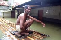 A man sits on a makeshift bamboo raft near his partially submerged house following flood due to monsoon rain at a village in Nagaon District of Assam. (Photo credit should read Anuwar Ali Hazarika/Barcroft Media via Getty Images)