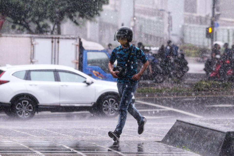 氣象局發布大雨特報，民眾快步跑向室內躲雨。（黃世麒攝）