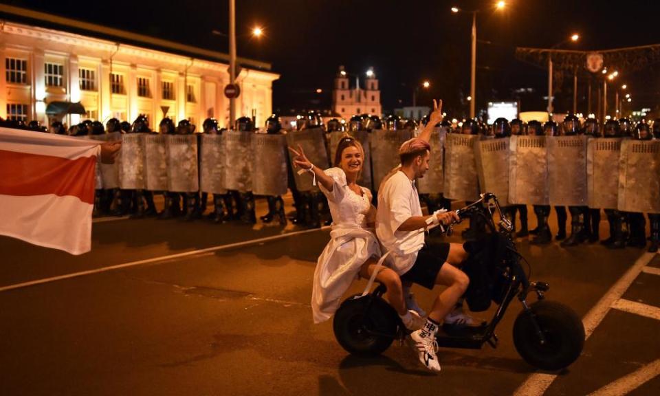 Protesters on a scooter face off with riot police after polls closed in Minsk