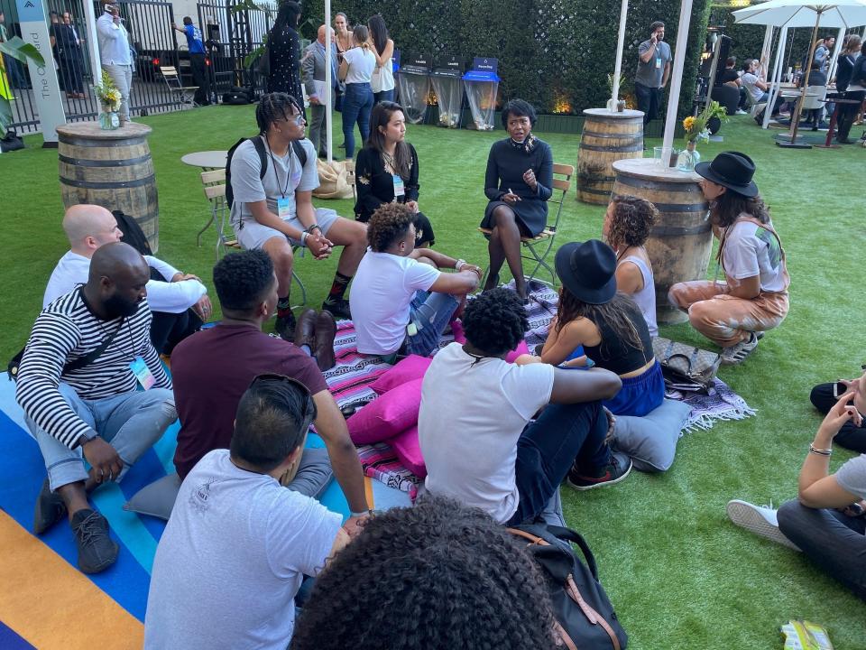 Mellody Hobson sits in chair speaking while group sits on ground surrounding her at SummitLA19