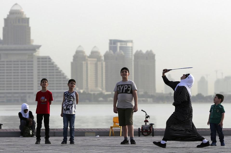 FILE - A woman plays badminton by the sea in front of the city skyline in Doha, Qatar, Friday, May 4, 2018. Qatar's residents squeezed as World Cup rental demand soars.(AP Photo/Kamran Jebreili, File)