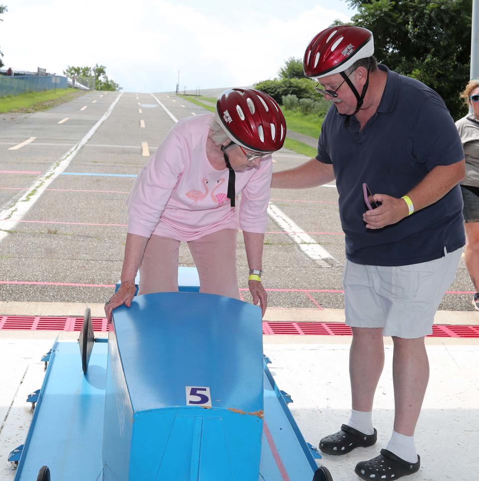 Rusty McCoy, right, assists his aunt Julie Callahan into her derby car as she prepares to race down the hill at Derby Downs during Senior Day on Thursday.