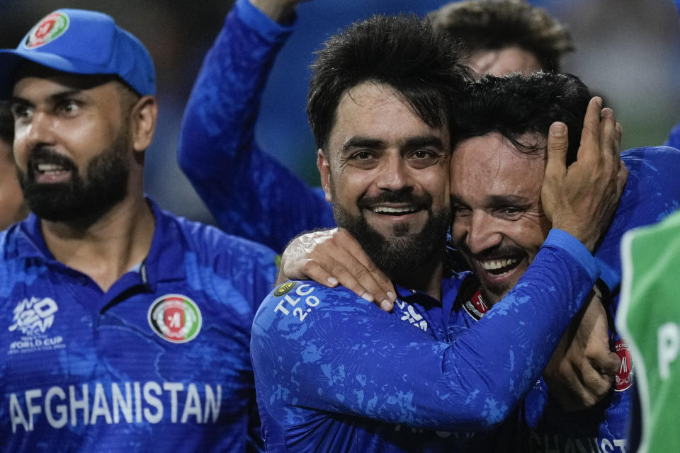 Afghanistan's captain Rashid Khan, centre, embraces teammate Gulbadin Naib as they celebrate after defeating Bangladesh by eight runs in their men's T20 World Cup cricket match at Arnos Vale Ground, Kingstown, Saint Vincent and the Grenadines, Monday, June 24, 2024. (AP Photo/Ricardo Mazalan)