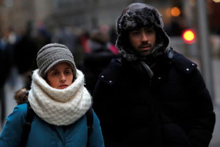 People walk along Wall Street ahead of a cold weather system across the region in Manhattan, New York City, U.S., December 28, 2016. REUTERS/Andrew Kelly