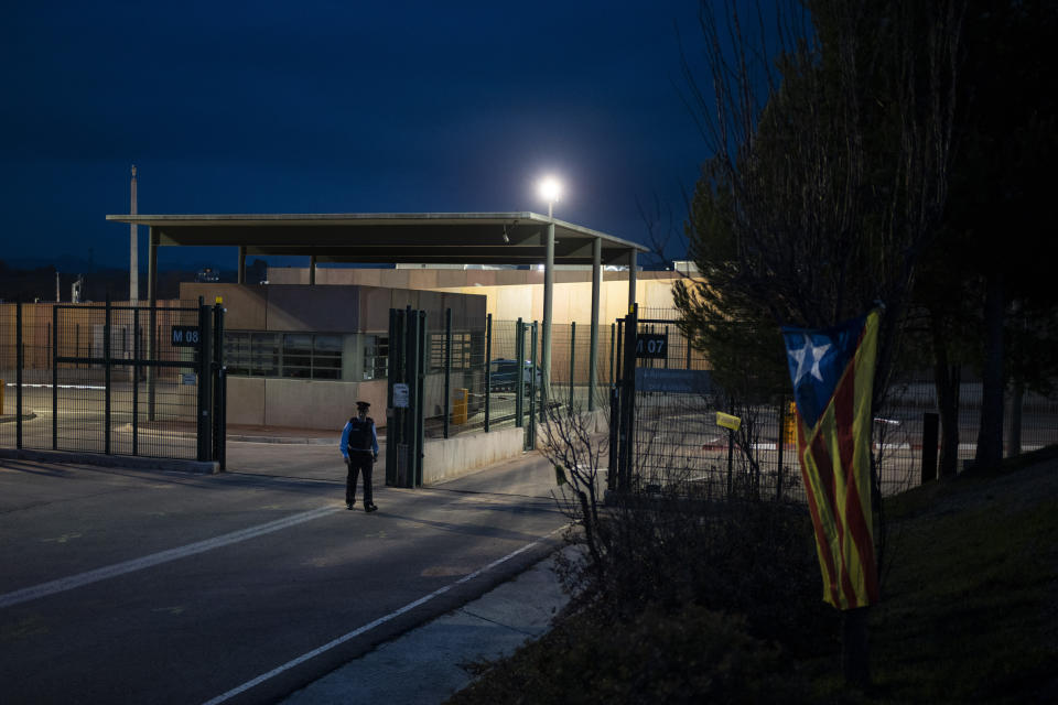 An estelada or independence flag, hangs from a tree as a policeman walks past the entrance of Lledoners prison, where former Catalan vice president Oriol Junqueras is currently serving a prison sentence in Sant Joan de Vilatorrada, near Barcelona, Spain, Thursday, Dec. 19, 2019. In a potentially stinging reversal for Spanish justice authorities, the European Union's top court ruled that the former Catalan official serving a prison sentence for his role in a banned independence referendum two years ago had the right to parliamentary immunity when he was on trial. (AP Photo/Felipe Dana)