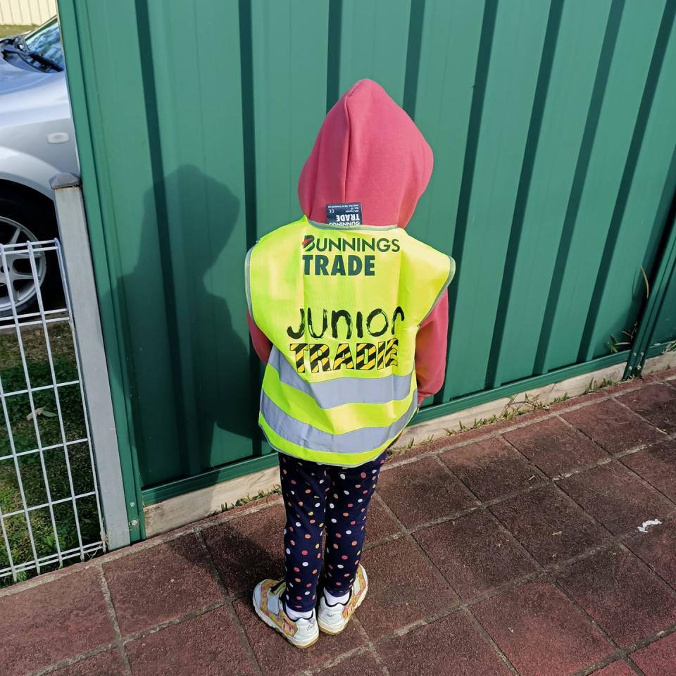 Child wearing Bunnings junior tradie fluro vest.