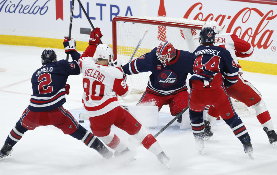 Winnipeg Jets goaltender Laurent Brossoit (39) makes a save against Detroit Red Wings' Michael Rasmussen, back right, during the first period of an NHL hockey game Wednesday, Dec. 20, 2023, in Winnipeg, Manitoba. (John Woods/The Canadian Press via AP)